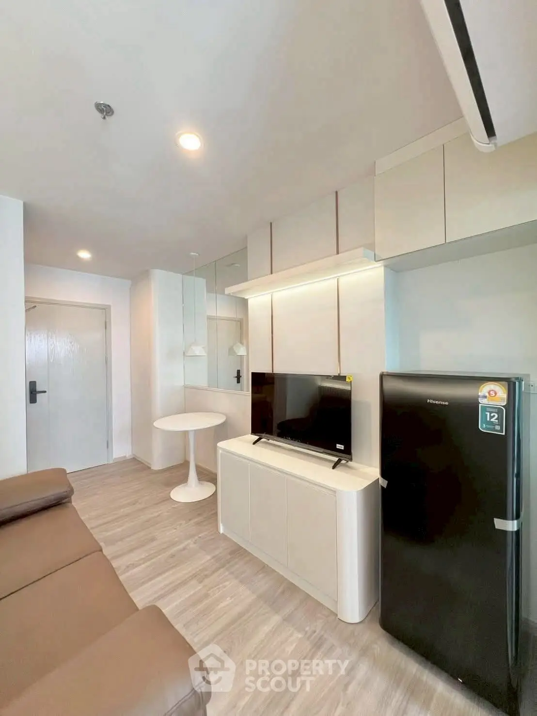 Modern living room with sleek furniture and appliances, featuring a cozy sofa and compact dining area.