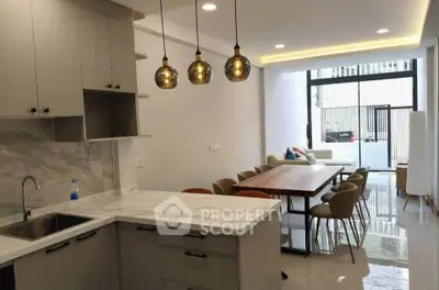 Modern open-layout kitchen and dining area with stylish lighting and marble countertops.