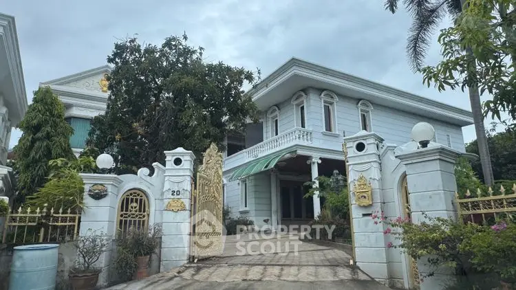 Stunning two-story mansion with elegant white facade and lush garden entrance.
