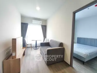Modern living room with cozy sofa and natural light, adjacent to a minimalist bedroom.