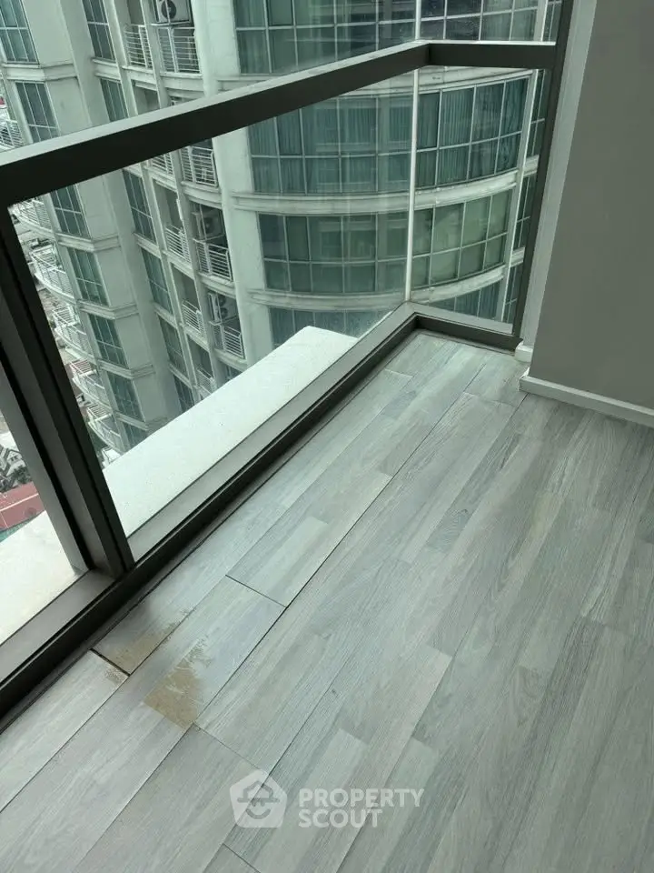Modern apartment with floor-to-ceiling windows offering stunning city views and sleek wooden flooring.