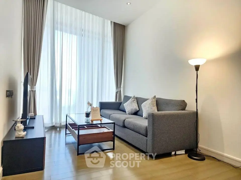 Modern living room with elegant decor and natural light, featuring a cozy sofa and stylish floor lamp.