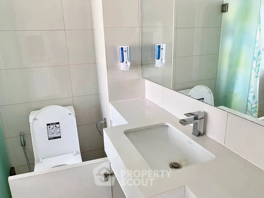 Modern bathroom with sleek sink and toilet, featuring clean lines and neutral tones.