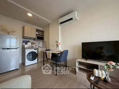 Modern living room with kitchen, featuring washing machine, fridge, and air conditioning.