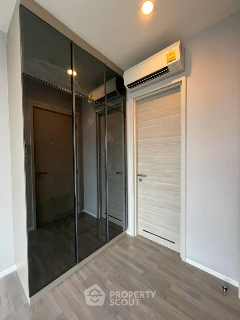Modern bedroom with sleek mirrored wardrobe and air conditioning unit