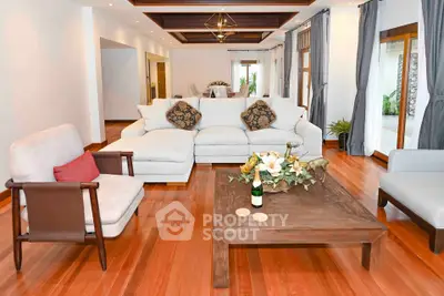 Spacious living room with elegant decor and wooden flooring, featuring cozy seating and stylish lighting.