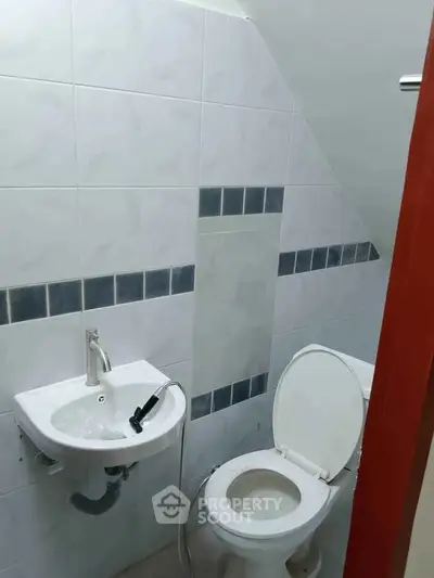 Compact bathroom with white toilet and small wall-mounted sink.
