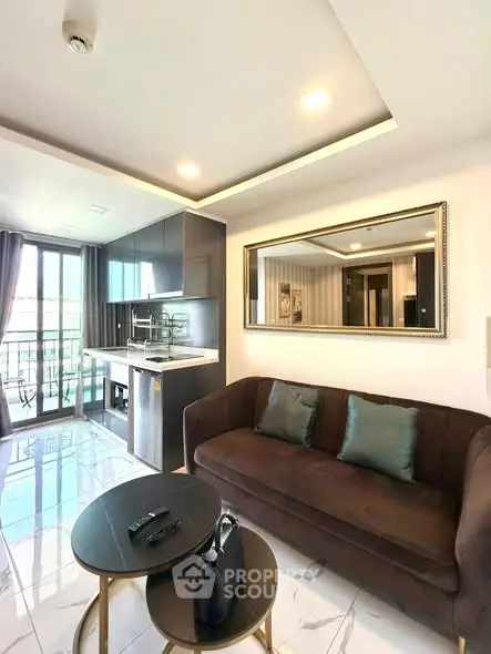 Modern living room with open kitchen and balcony view, featuring sleek furniture and elegant decor.