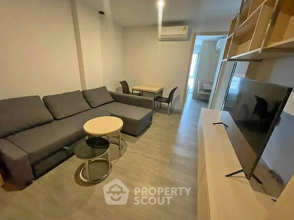 Modern living room with sleek furniture and wall-mounted air conditioning unit.