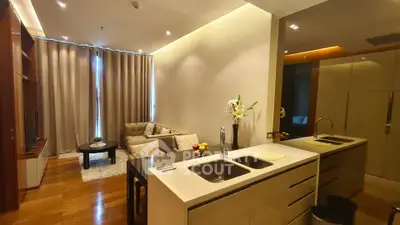 Modern open-layout living room with sleek kitchen, cozy seating, and elegant decor.