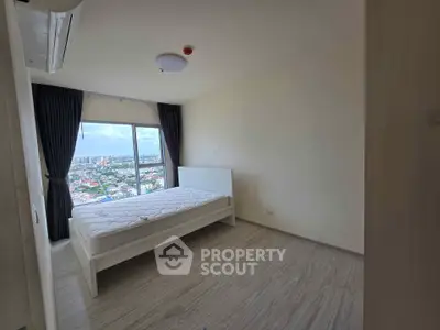 Spacious bedroom with large window offering stunning city views, modern minimalist design, and ample natural light.