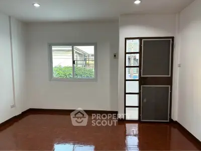 Spacious empty room with polished wooden floor and large window, perfect for customization.