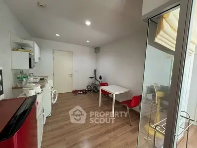 Modern apartment interior with open kitchen and dining area, featuring sleek appliances and wooden flooring.