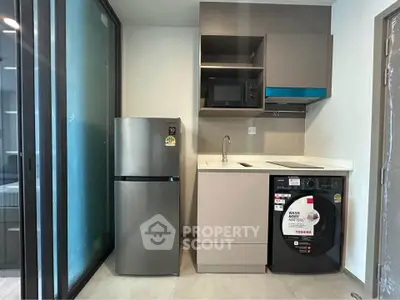 Modern compact kitchen with fridge, microwave, and washing machine