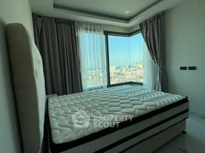 Modern bedroom with large windows offering stunning city views and elegant curtains.