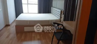 Modern bedroom with wooden flooring and stylish bed frame, featuring a large window for natural light.