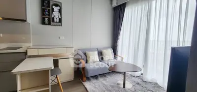 Modern living room with cozy sofa and large window with sheer curtains.