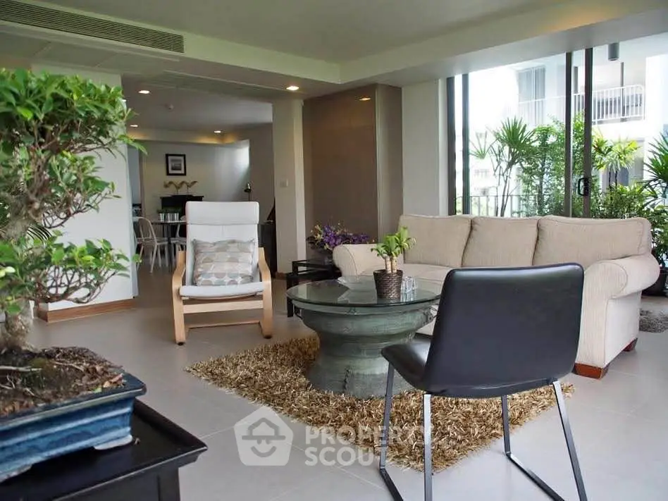 Spacious living room with modern furniture and large windows offering garden views.