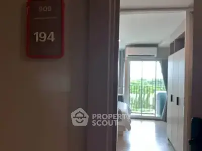 Modern apartment entrance leading to a bright bedroom with balcony view.