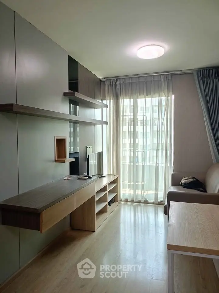 Modern living room with sleek furniture and large window offering natural light.