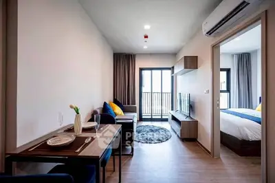 Modern open-plan living room with dining area and bedroom in a stylish apartment.