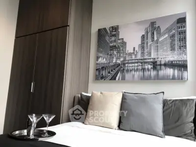 Modern bedroom with stylish decor and cityscape artwork, featuring sleek furniture and elegant design.
