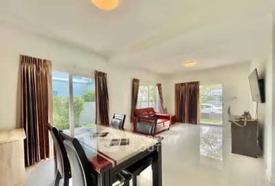 Spacious living room with modern furniture and large windows offering garden views.