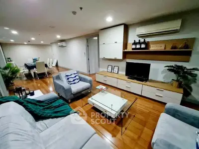 Spacious living room with modern furniture and dining area, featuring wooden flooring and stylish decor.