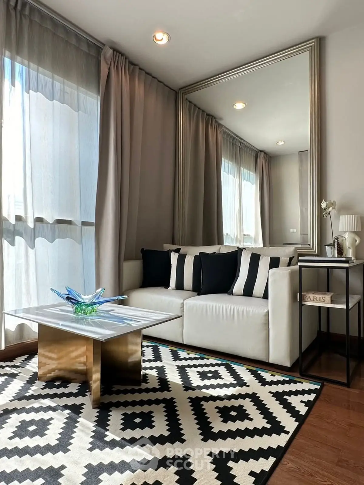 Stylish living room with modern decor, large mirror, and natural light.