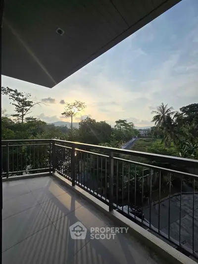 Spacious balcony with stunning sunset view and lush greenery, perfect for relaxation and outdoor enjoyment.
