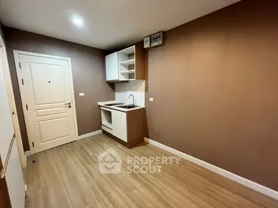 Modern minimalist kitchen with sleek cabinetry and wood flooring in a compact space.