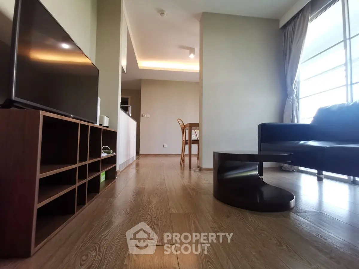 Modern living room with sleek furniture and wooden flooring, featuring a cozy sofa and entertainment unit.