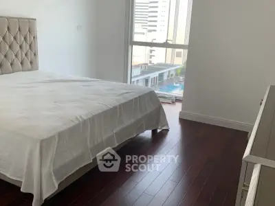 Spacious bedroom with elegant hardwood floors and a view of the cityscape.