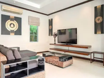 Modern living room with stylish decor and large flat-screen TV, featuring elegant furniture and natural light.