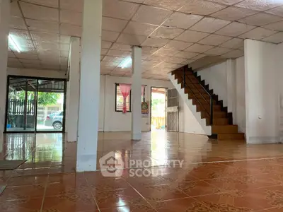 Spacious open-plan living area with tiled flooring and staircase