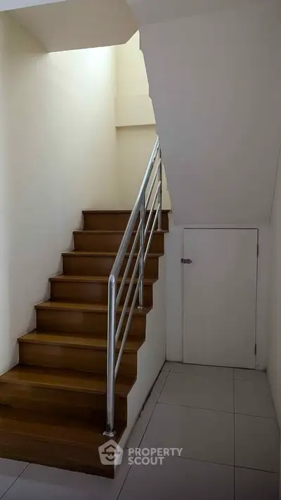 Modern staircase with wooden steps and metal railing in a minimalist interior.