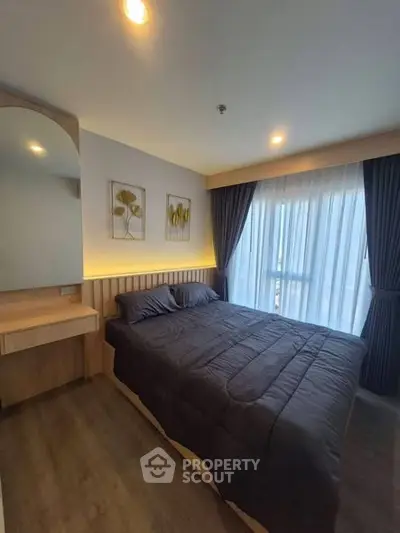 Modern bedroom with cozy bedding and natural light from large window