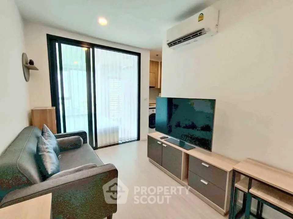 Modern living room with sleek furniture and large TV, featuring a cozy ambiance and efficient use of space.
