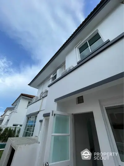 Modern two-story white house with large windows and clear blue sky