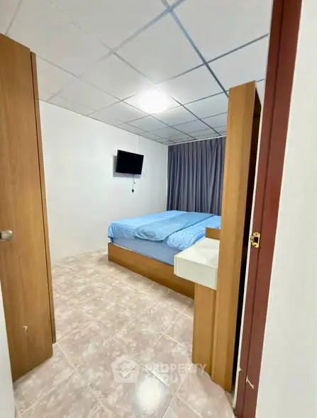 Cozy bedroom with modern decor and wall-mounted TV, perfect for relaxation.