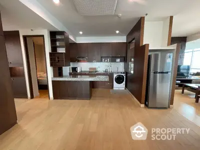 Modern open-plan kitchen with sleek appliances and wooden cabinetry in a spacious apartment.