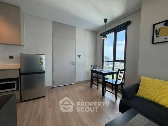 Modern apartment interior with kitchen and dining area, featuring sleek appliances and a bright window view.