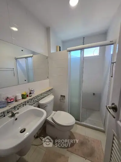 Modern bathroom with shower and sleek fixtures in a bright, tiled space.