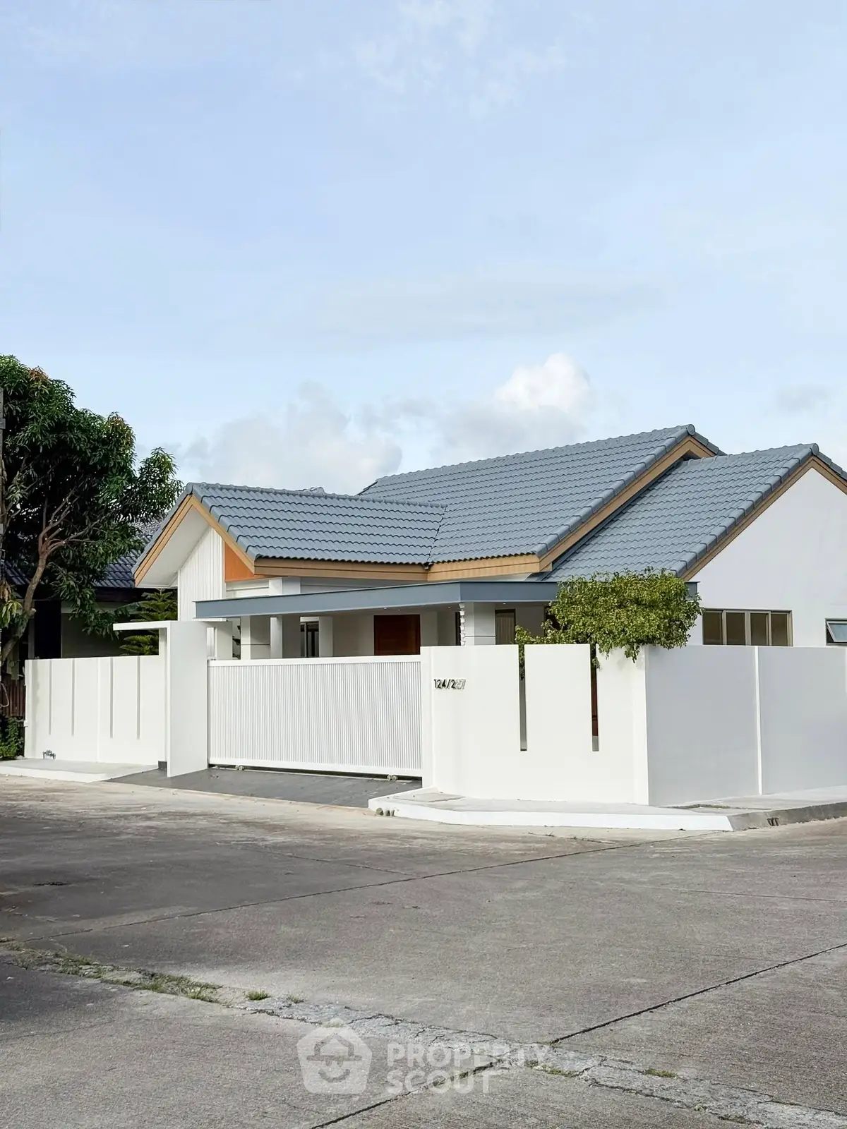 Charming suburban home with modern white fence and blue roof, perfect for family living.