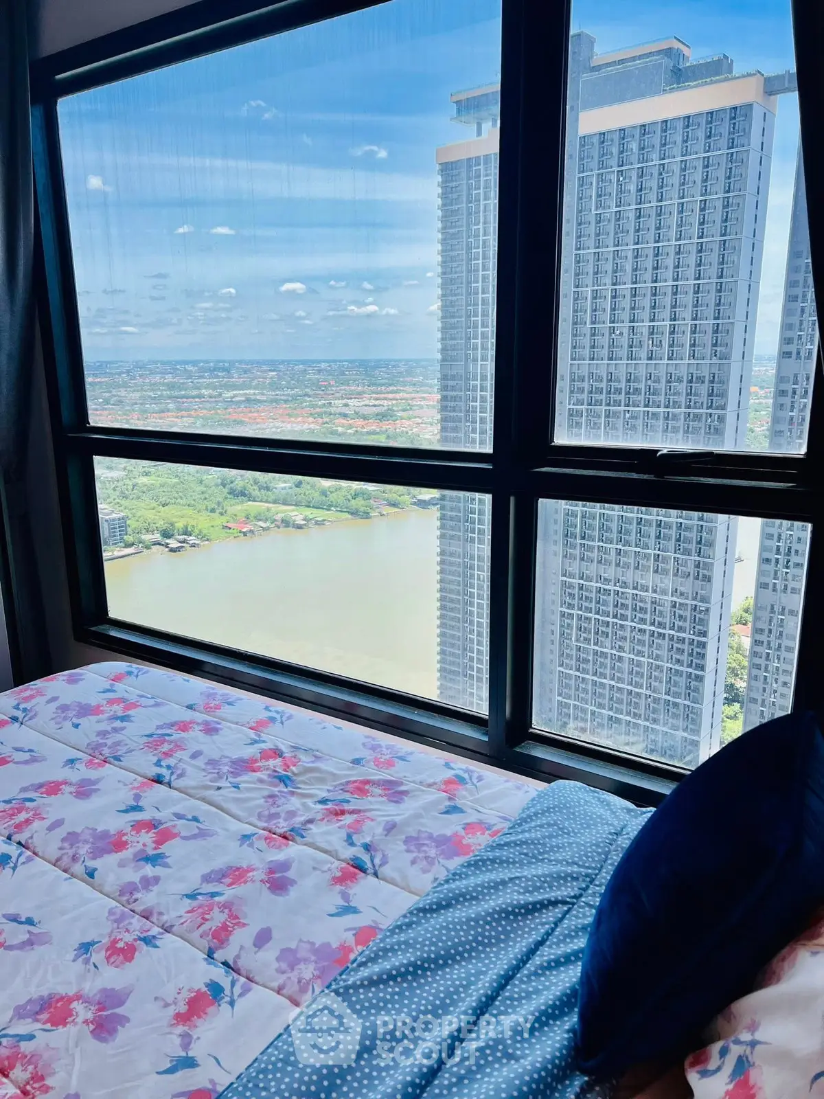 Stunning high-rise bedroom view with river and cityscape panorama.