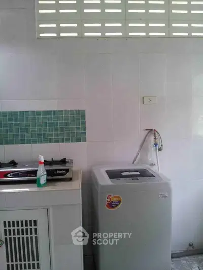 Compact kitchen with washing machine and gas stove in modern home.