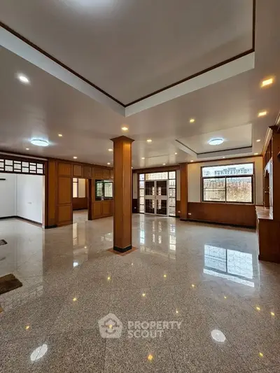 Spacious open-plan living room with polished floors and large windows in a modern apartment.