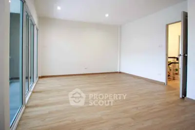 Spacious empty room with wooden flooring and large windows for natural light.