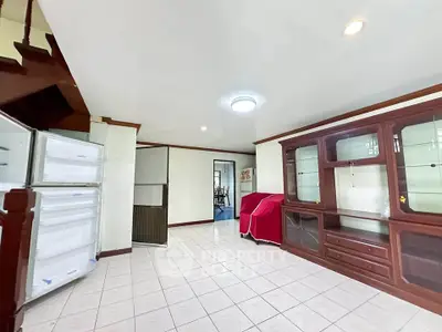 Spacious living room with built-in wooden cabinets and tiled flooring, ideal for family gatherings.