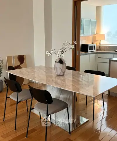 Elegant dining area with marble table and modern kitchen in open layout apartment.